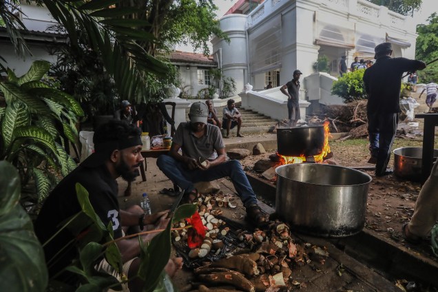 Pessoas cozinham em fogo aberto no jardim da residência oficial do primeiro-ministro em Colombo, Sri Lanka, 10/07/2022, um dia depois de invadir residências oficiais. O presidente e o primeiro-ministro do Sri Lanka concordaram em renunciar após uma reunião de líderes do partido durante um dia de protestos contra o governo em massa.  EFE/EPA/CHAMILA KARUNARATHNE
