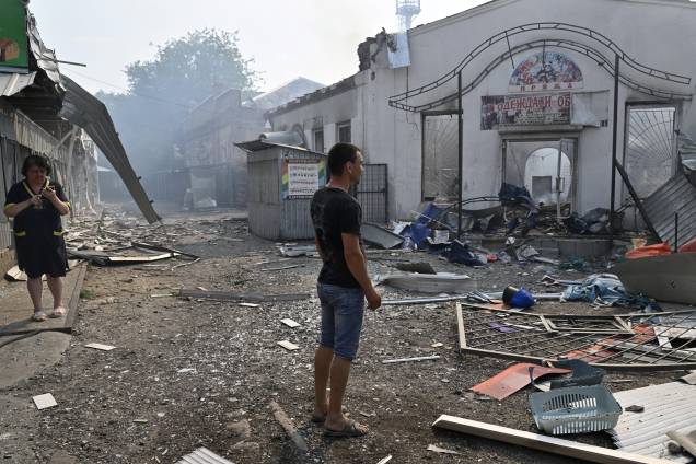 Moradores locais observam lojas destruídas em um mercado local após um ataque com foguete na cidade ucraniana de Sloviansk, em 03/07/2022, em meio à invasão russa da Ucrânia.