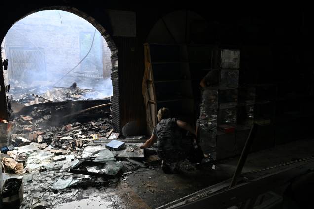 Uma vendedora recolhe algumas mercadorias de uma loja destruída em um mercado local após um ataque com foguete na cidade ucraniana de Sloviansk, em 03/07/2022, em meio à invasão russa da Ucrânia.