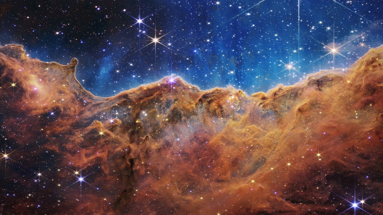 Esta paisagem de “montanhas” e “vales” salpicados de estrelas brilhantes é na verdade a borda de uma região jovem e próxima de formação de estrelas chamada NGC 3324 na Nebulosa Carina