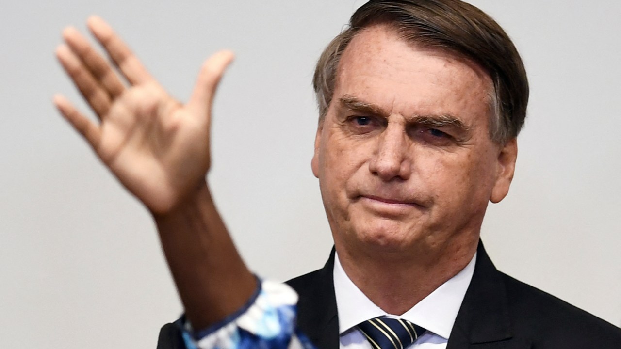 Brazilian President and candidate for reelection for the Liberal Party, Jair Bolsonaro, looks on as someone gestures in front of him during an evangelical service at the National Congress' Lower House in Brasilia, on August 3, 2022. - Bolsonaro trails former president Luiz Inacio Lula da Silva with the presidential election just two months away. (Photo by EVARISTO SA / AFP)