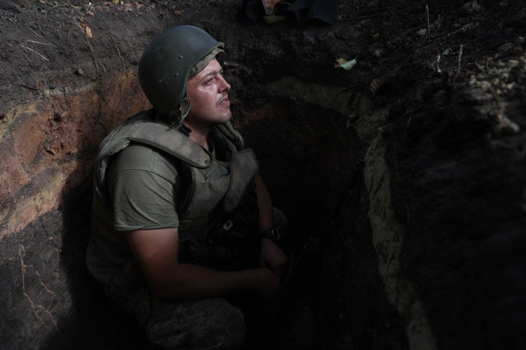 A Ukrainian soldier sits in a foxhole at a position along the front line in the Donetsk region on August 15, 2022, amid Russia's invasion of Ukraine. (Photo by Anatolii Stepanov / AFP)