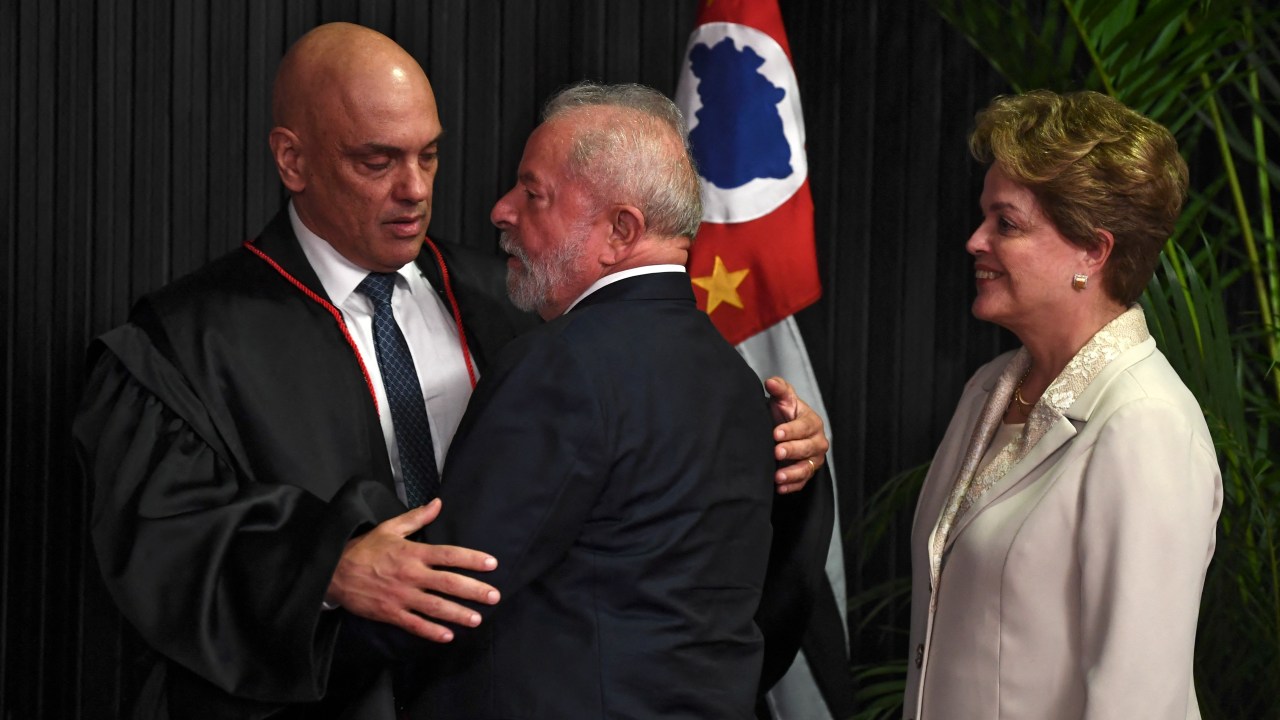 Brazilian presidential candidate for the leftist Workers Party (PT) and former President (2003-2010), Luiz Inacio Lula da Silva (C) greets Brazilian judge Alexandre de Moraes (L) after he took over as head of the Superior Electoral Tribunal, as Brazil's ex-president Dilma Rousseff follows, at the TSE headquarters in Brasilia, on August 16, 2022. - The TSE is the institution responsible for refereeing the South American giant's October elections and punishing violations of electoral law. Openly reviled by President Jair Bolsonaro, de Moraes may have to show the stuff that earned him the nickname "RoboCop" as arbiter in polarizing, disinformation-plagued elections to decide the far-right incumbent's fate. (Photo by EVARISTO SA / AFP)