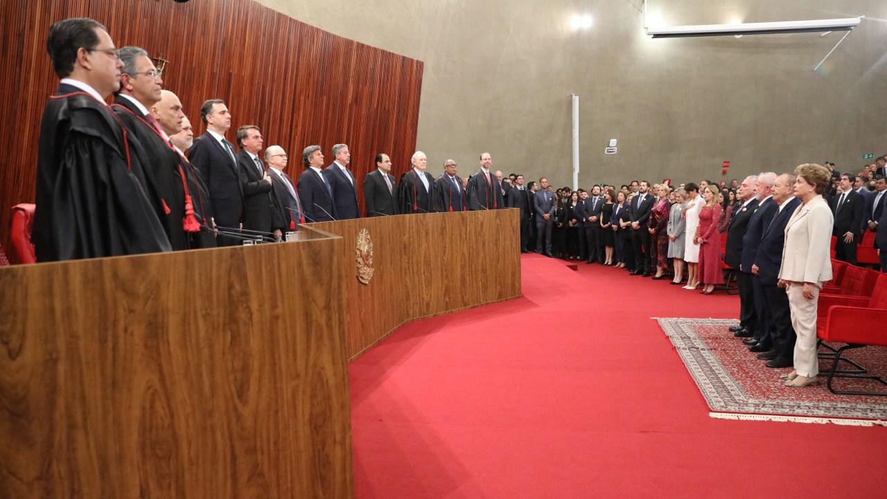 Handout picture released by the Social Communication Secretariat (Secom) via Brazil's Superior Electoral Tribunal (TSE) showing a general view of the ceremony in which Brazilian judge Alexandre de Moraes (3-L) takes over as head of the Superior Electoral Tribunal, at the TSE headquarters in Brasilia, on August 16, 2022, while Brazilian President Jair Bolsonaro (6-L) takes his hand to the heart, and former president stand in front of them (R). - The TSE is the institution responsible for refereeing the South American giant's October elections and punishing violations of electoral law. Openly reviled by President Jair Bolsonaro, de Moraes may have to show the stuff that earned him the nickname "RoboCop" as arbiter in polarizing, disinformation-plagued elections to decide the far-right incumbent's fate. (Photo by Antonio AUGUSTO / TSE / AFP) / RESTRICTED TO EDITORIAL USE - MANDATORY CREDIT "AFP PHOTO / TSE / SECOM / ANTONIO AUGUSTO " - NO MARKETING - NO ADVERTISING CAMPAIGNS - DISTRIBUTED AS A SERVICE TO CLIENTS