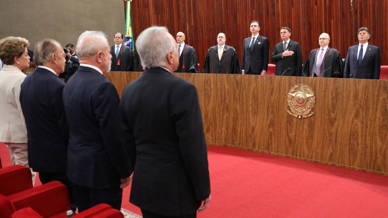 Handout picture released by the Social Communication Secretariat (Secom) via Brazil's Superior Electoral Tribunal (TSE) showing (foreground R-L) Brazil's ex presidents Michel Temer, Luiz Inacio Lula da Silva, Jose Sarney and Dilma Rousseff standing during the ceremony in which Brazilian judge Alexandre de Moraes (6-R) takes over as head of the Superior Electoral Tribunal, at the TSE headquarters in Brasilia, on August 16, 2022, while Brazilian President Jair Bolsonaro (3-R) takes his hand to the heart. - The TSE is the institution responsible for refereeing the South American giant's October elections and punishing violations of electoral law. Openly reviled by President Jair Bolsonaro, de Moraes may have to show the stuff that earned him the nickname "RoboCop" as arbiter in polarizing, disinformation-plagued elections to decide the far-right incumbent's fate. (Photo by Antonio AUGUSTO / TSE / AFP) / RESTRICTED TO EDITORIAL USE - MANDATORY CREDIT "AFP PHOTO / TSE / SECOM / ANTONIO AUGUSTO " - NO MARKETING - NO ADVERTISING CAMPAIGNS - DISTRIBUTED AS A SERVICE TO CLIENTS