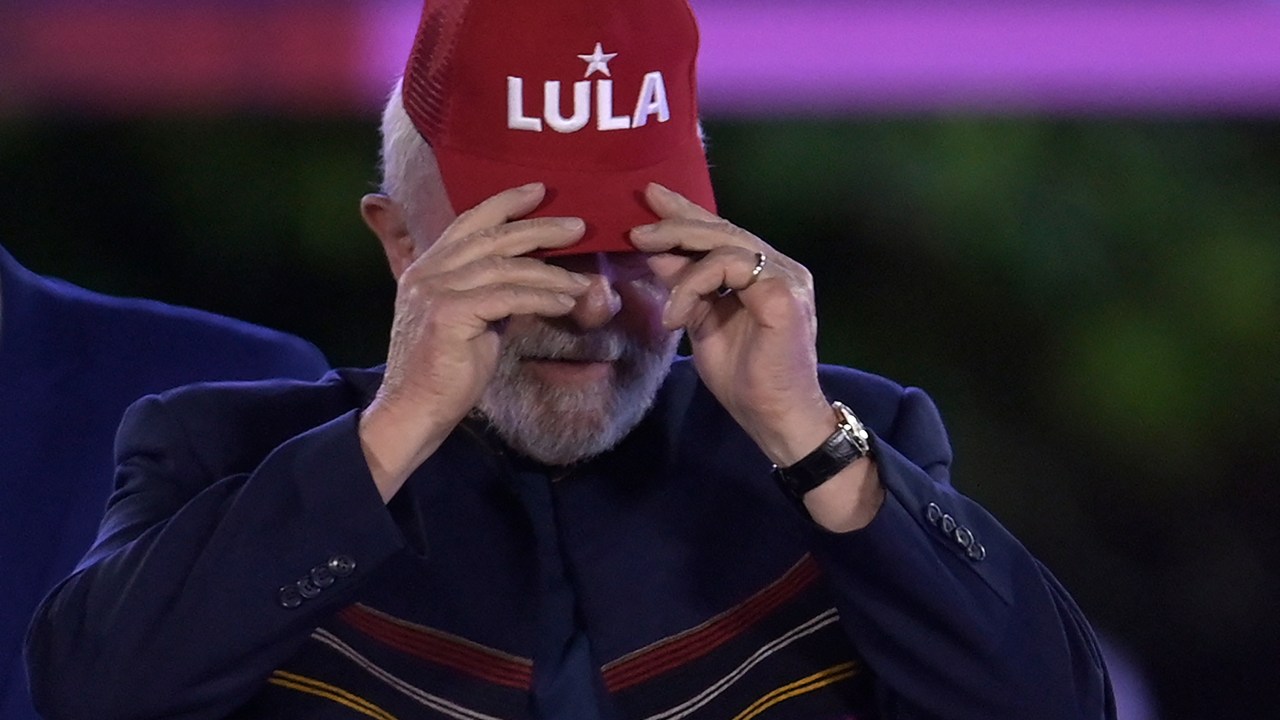 Brazil's ex-president Luiz Inacio Lula da Silva puts a cap on during a political gathering as part of his campaign for the presidency, at Praca da Liberdade in Belo Horizonte, Minas Gerais State, Brazil, on August 18, 2022. - Brazil holds presidential elections on October 2. (Photo by Douglas MAGNO / AFP)