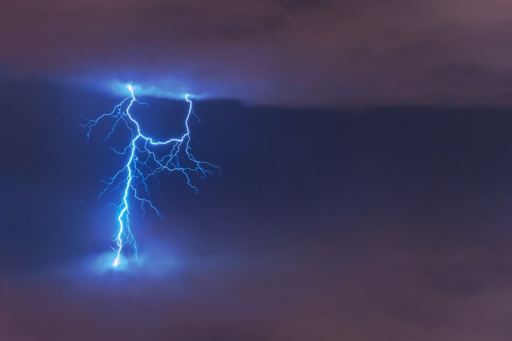 Lightning strike flash, electric discharge between clouds at night