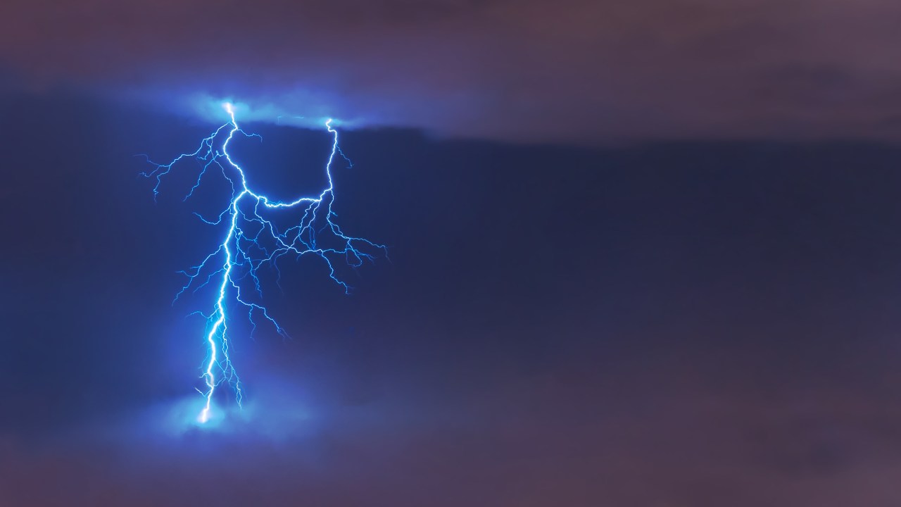 Lightning strike flash, electric discharge between clouds at night