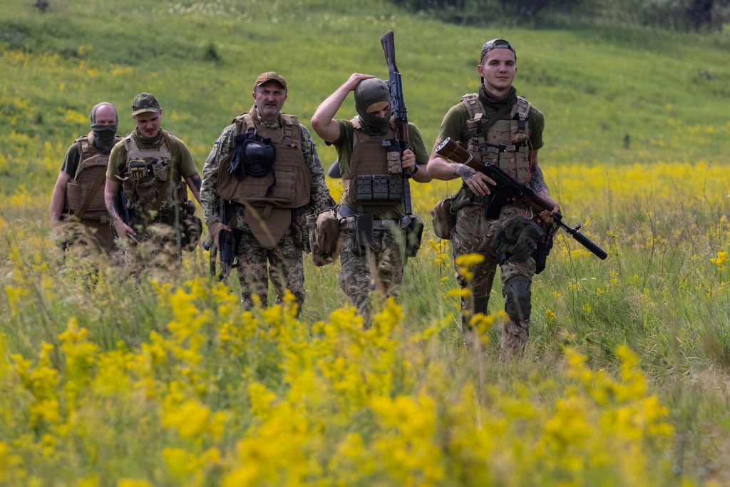 KHARKIV REGION, UKRAINE - JUNE 28: Azov Regiment soldiers walk through a field for tactical training on June 28, 2022 in the Kharkiv region, Ukraine.The Azov Regiment was founded as a paramilitary group in 2014 to fight pro-Russian forces in the Donbas War, and was later incorporated into Ukraine's National Guard as Special Operations Detachment "Azov." The group, which takes its name from the Sea of Azov, has drawn controversy due to its far-right roots, which Russian President Vladimir Putin has tried to exploit to portray his war as a fight against "Nazis." Azov battalion members were among those forced to surrender to Russia at Mariupol's Azovstal steel plant last month, after holding out amid months of intense bombardment, during which time they were celebrated as heroes by their compatriots and Ukrainian President Volodymyr Zelensky. (Photo by Paula Bronstein/Getty Images)