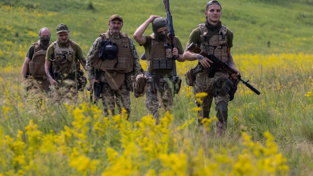 KHARKIV REGION, UKRAINE - JUNE 28: Azov Regiment soldiers walk through a field for tactical training on June 28, 2022 in the Kharkiv region, Ukraine.The Azov Regiment was founded as a paramilitary group in 2014 to fight pro-Russian forces in the Donbas War, and was later incorporated into Ukraine's National Guard as Special Operations Detachment "Azov." The group, which takes its name from the Sea of Azov, has drawn controversy due to its far-right roots, which Russian President Vladimir Putin has tried to exploit to portray his war as a fight against "Nazis." Azov battalion members were among those forced to surrender to Russia at Mariupol's Azovstal steel plant last month, after holding out amid months of intense bombardment, during which time they were celebrated as heroes by their compatriots and Ukrainian President Volodymyr Zelensky. (Photo by Paula Bronstein/Getty Images)