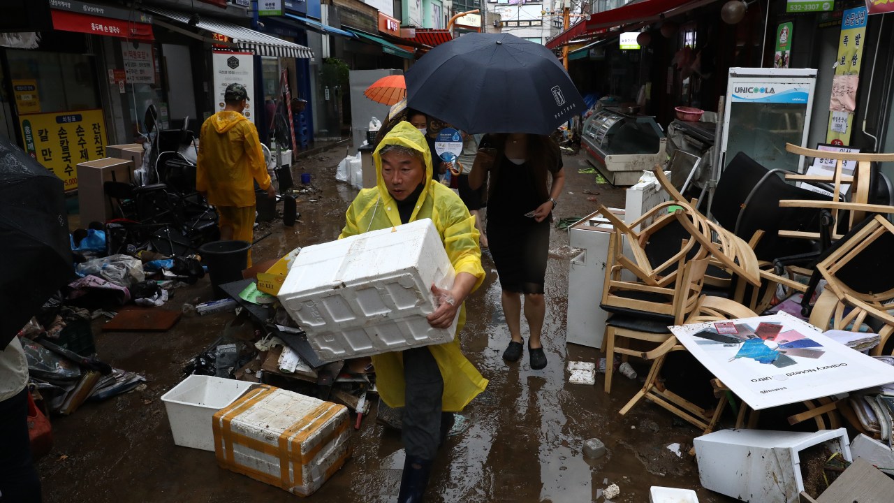 SEOUL, SOUTH KOREA - AUGUST 09: People clean up debris at a traditional market damaged by flood after torrential rain on August 09, 2022 in Seoul, South Korea. The heaviest rainfall in 80 years has pounded Seoul and surrounding regions, leaving seven people dead and six others missing, as well as flooding homes, vehicles, buildings and subway stations, government officials said. (Photo by Chung Sung-Jun/Getty Images)