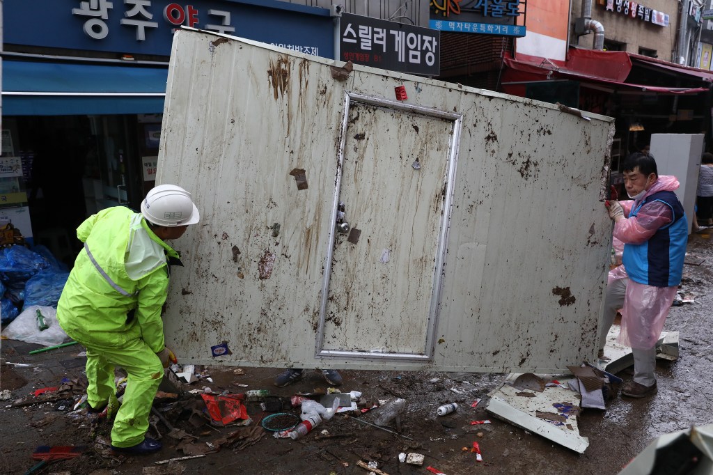 SEOUL, SOUTH KOREA - AUGUST 09: People clean up debris at a traditional market damaged by flood after torrential rain on August 09, 2022 in Seoul, South Korea. The heaviest rainfall in 80 years has pounded Seoul and surrounding regions, leaving seven people dead and six others missing, as well as flooding homes, vehicles, buildings and subway stations, government officials said. (Photo by Chung Sung-Jun/Getty Images)