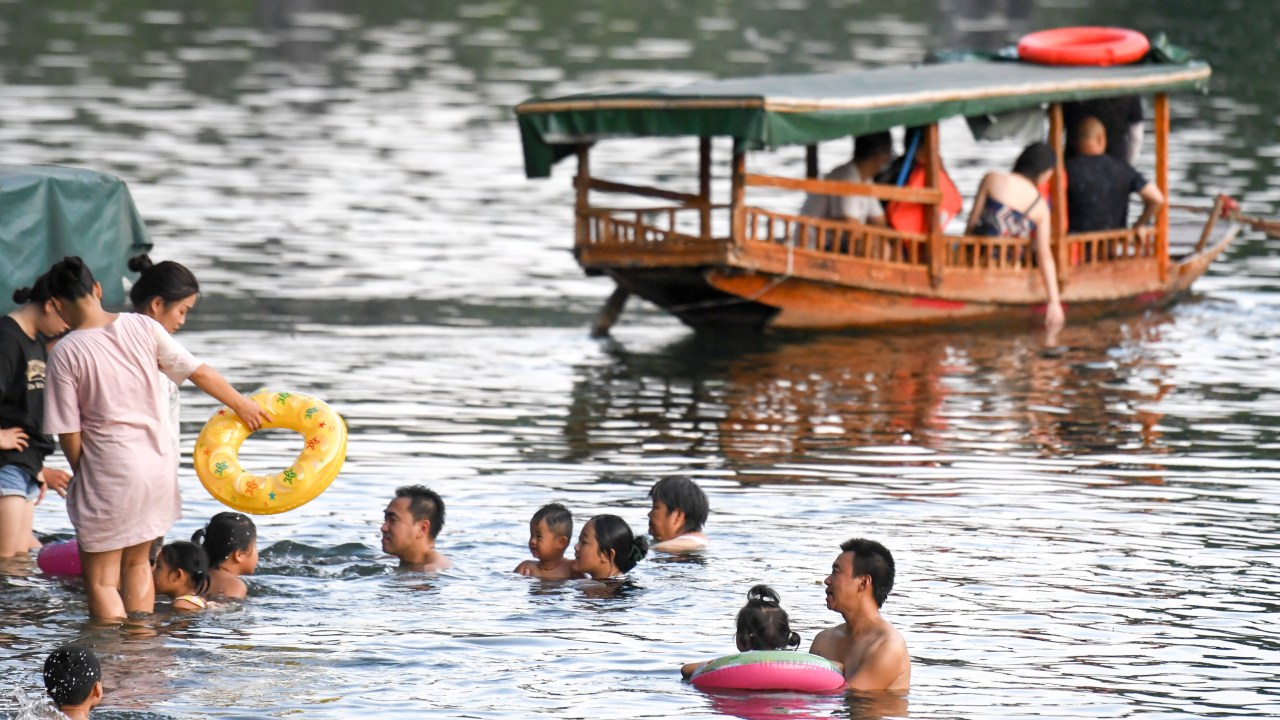XIANGXI, CHINA - 15 DE AGOSTO: Pessoas se banham em um rio para se refrescar no clima quente em 15 de agosto de 2022 na Prefeitura Autônoma de Xiangxi Tujia e Miao, província de Hunan, na China.