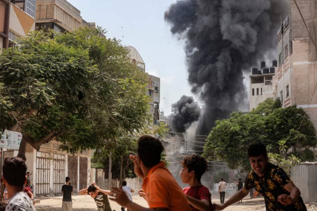 Jovens correm para se proteger durante o bombardeio aéreo israelense na Cidade de Gaza em 06/08/2022. Jovens correm para se proteger durante o bombardeio aéreo israelense na Cidade de Gaza em 06/08/2022.