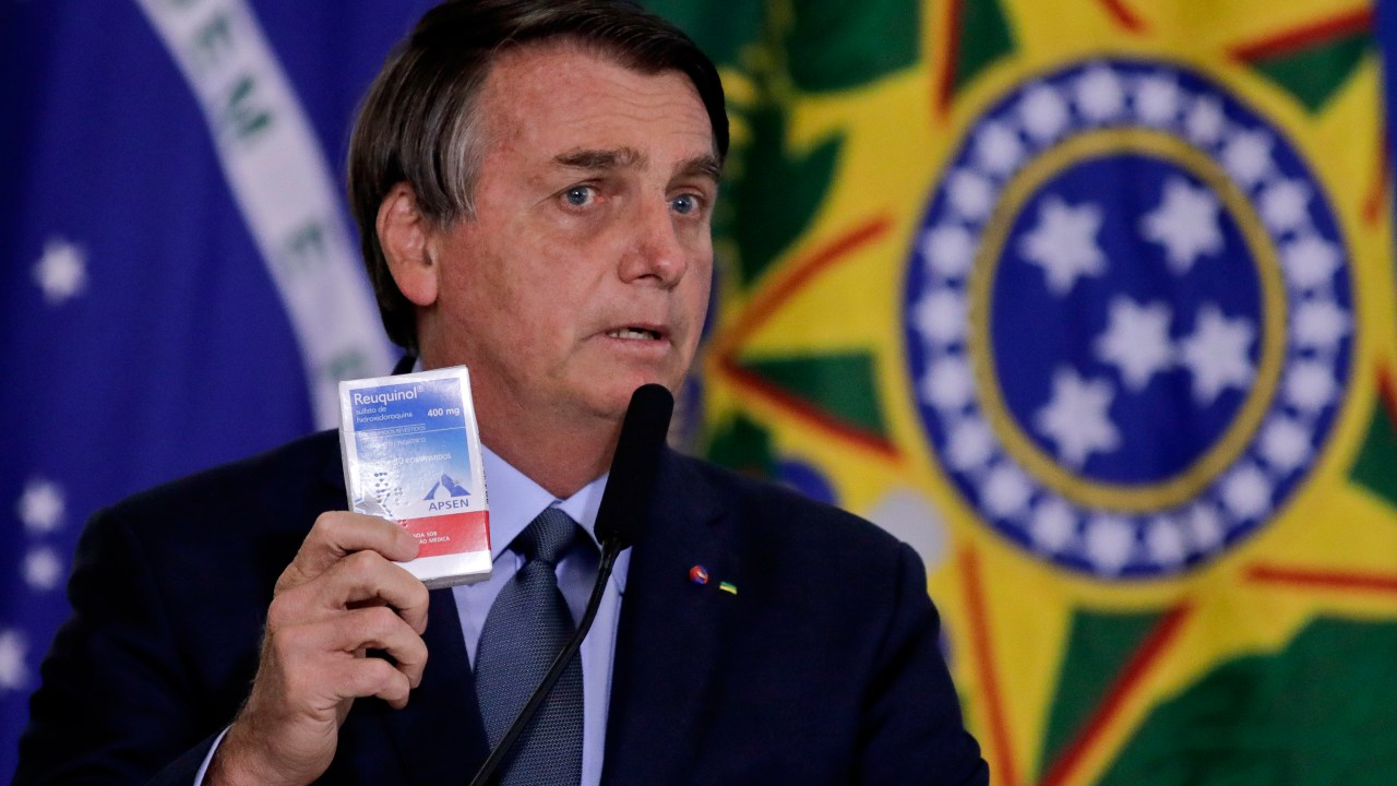 Bolsonaro segurando uma caixa de hidroxicloroquina - erros da pandemia reproduzidos diante das cartas pela democracia