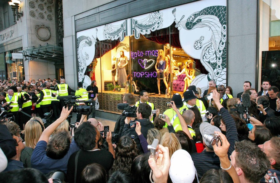 Pessoas se reúnem do lado de fora de uma loja Top Shop, na vitrini a top model britânica Kate Moss promove sua nova linha de roupas, Londres, 30/04/2007.