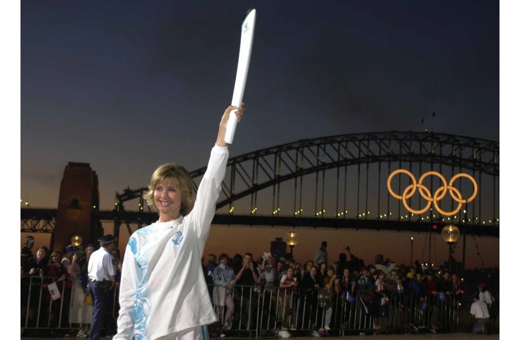A atriz e cantora anglo-australiana Olivia Newton-John, ergue a tocha olímpica dos jogos de Sydney, em 14/09/2000.