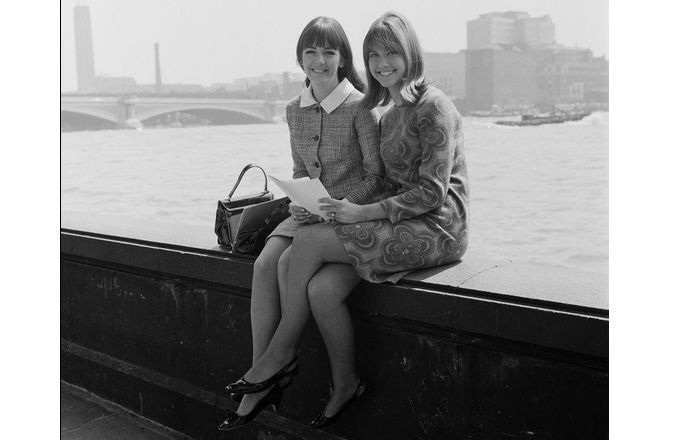 A atriz e cantora anglo-australiana Olivia Newton-John e sua amiga de escola musical Pat Carroll, em Londres, 1966.