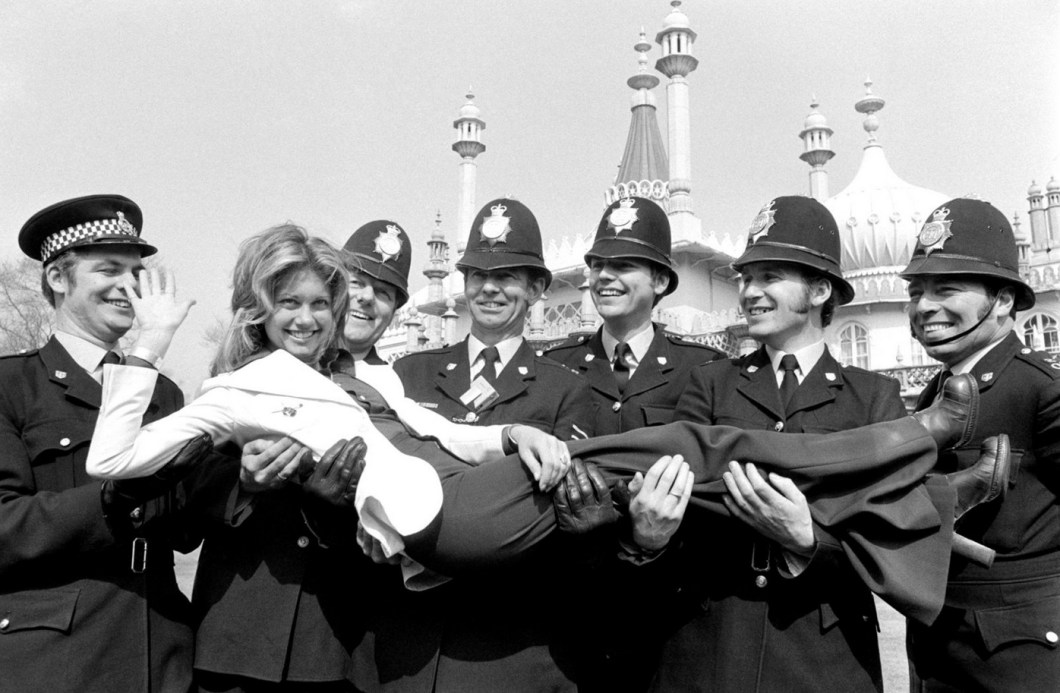 A atriz e cantora anglo-australiana Olivia Newton-John, com os policiais de Brighton, Inglaterra, 1974.