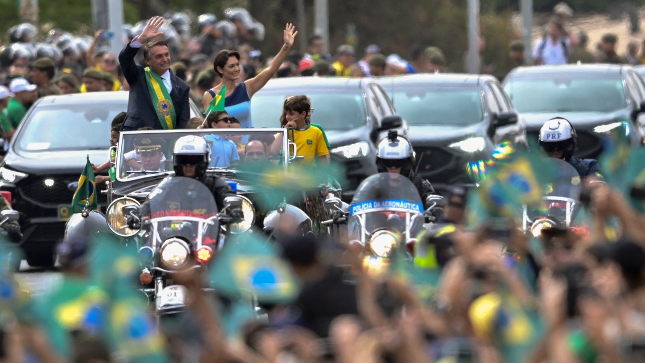 Brazilian President Jair Bolsonaro (L) and First Lady Michelle Bolsonaro wave during a military parade to mark Brazil's 200th anniversary of independence in Brasilia, on September 7, 2022. (Photo by EVARISTO SA / AFP)