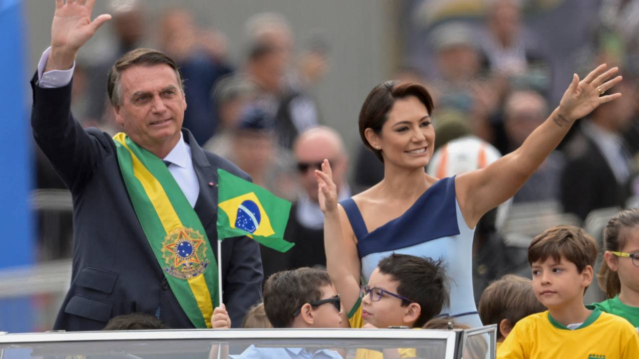 Brazilian President Jair Bolsonaro (L) and First Lady Michelle Bolsonaro wave during a military parade to mark Brazil's 200th anniversary of independence in Brasilia, on September 7, 2022. (Photo by EVARISTO SA / AFP)