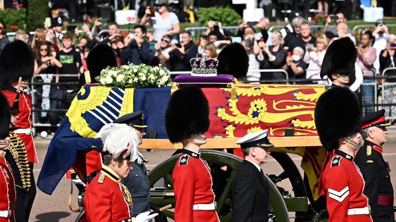 O caixão da Rainha Elizabeth II, adornado com um Estandarte Real e a Coroa Imperial do Estado e puxado por uma Carruagem da Tropa Real de Artilharia do Rei, é retratado durante uma procissão do Palácio de Buckingham ao Palácio de Westminster, em Londres, em 14 de setembro. , 2022. - A rainha Elizabeth II ficará em estado no Westminster Hall, dentro do Palácio de Westminster, de quarta-feira até algumas horas antes de seu funeral na segunda-feira, com enormes filas esperadas para passar por seu caixão para prestar homenagem. (Foto de Marco BERTORELLO/AFP)