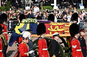 O caixão da Rainha Elizabeth II, adornado com um Estandarte Real e a Coroa Imperial do Estado e puxado por uma Carruagem da Tropa Real de Artilharia do Rei, é retratado durante uma procissão do Palácio de Buckingham ao Palácio de Westminster, em Londres, em 14 de setembro. , 2022. - A rainha Elizabeth II ficará em estado no Westminster Hall, dentro do Palácio de Westminster, de quarta-feira até algumas horas antes de seu funeral na segunda-feira, com enormes filas esperadas para passar por seu caixão para prestar homenagem. (Foto de Marco BERTORELLO/AFP)