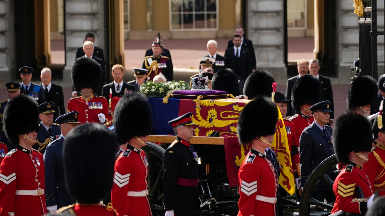 The coffin of Queen Elizabeth II, adorned with a Royal Standard and the Imperial State Crown and pulled by a Gun Carriage of The King's Troop Royal Horse Artillery, is seen during a procession from Buckingham Palace to the Palace of Westminster, in London on September 14, 2022. - Queen Elizabeth II will lie in state in Westminster Hall inside the Palace of Westminster, from Wednesday until a few hours before her funeral on Monday, with huge queues expected to file past her coffin to pay their respects. (Photo by Christophe Ena / POOL / AFP)