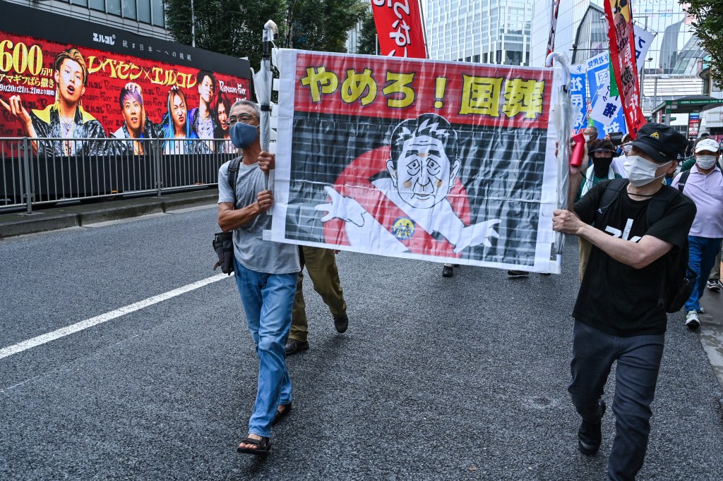 Protesters hold a banner with an image of late Japanese prime minister Shinzo Abe as anti-war, anti-nuclear and protesters against the government's funding for Abe's funeral take part in a rally and march in Tokyo on September 19, 2022. - Japan expects to spend around 12 million USD on a state funeral on September 27 for assassinated former premier Shinzo Abe, the government said on September 6, despite controversy over the plan. (Photo by Richard A. Brooks / AFP)