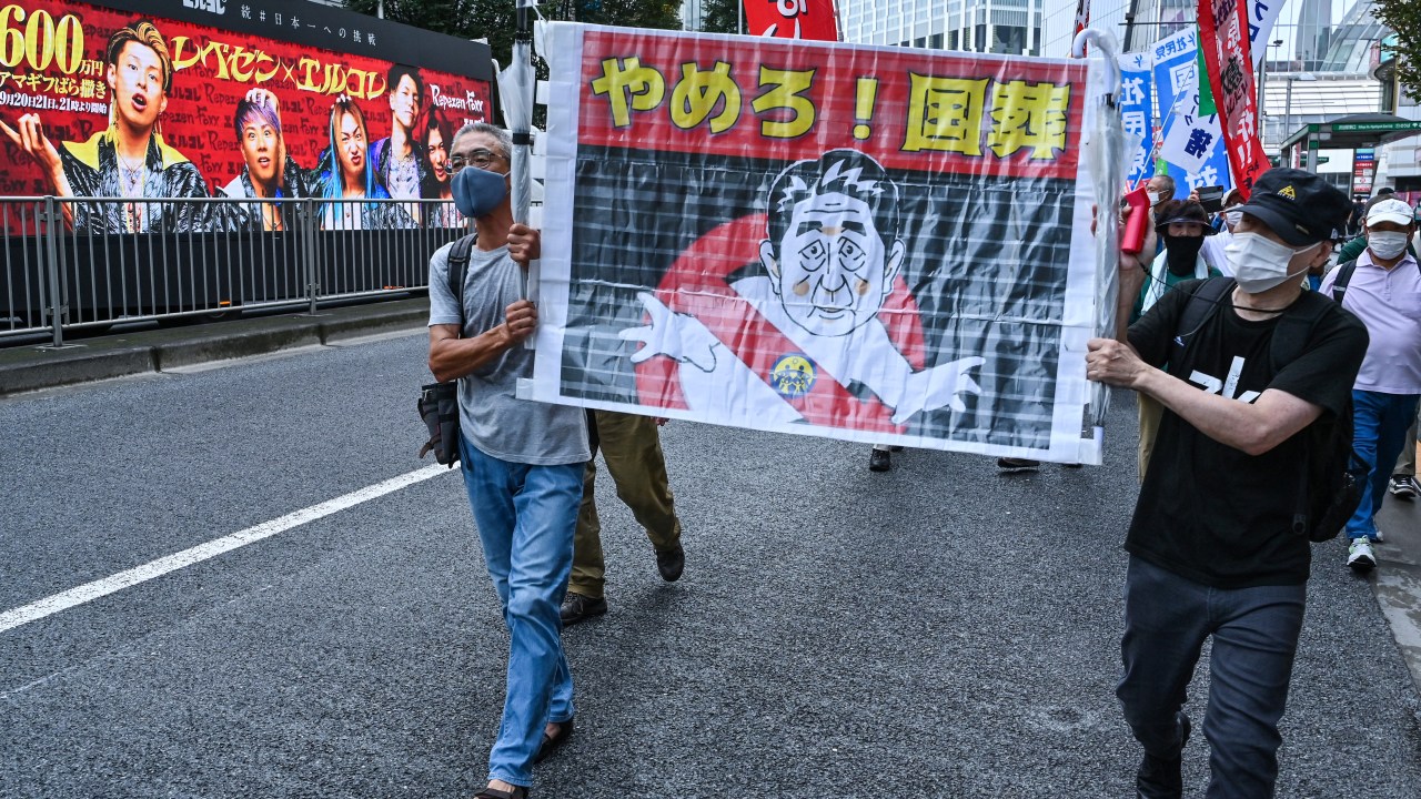 Protesters hold a banner with an image of late Japanese prime minister Shinzo Abe as anti-war, anti-nuclear and protesters against the government's funding for Abe's funeral take part in a rally and march in Tokyo on September 19, 2022. - Japan expects to spend around 12 million USD on a state funeral on September 27 for assassinated former premier Shinzo Abe, the government said on September 6, despite controversy over the plan. (Photo by Richard A. Brooks / AFP)