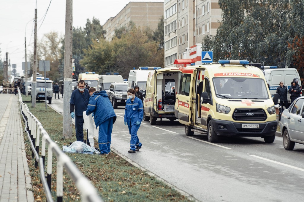 Medics gather at the body of a dead person near the scene of a shooting in school No88 in Izhevsk on September 26, 2022. - The death toll has risen to 13 people, including seven children, after a man opened fire on September 26 at his former school in central Russia, authorities said. (Photo by Maria BAKLANOVA / Kommersant Photo / AFP) / Russia OUT