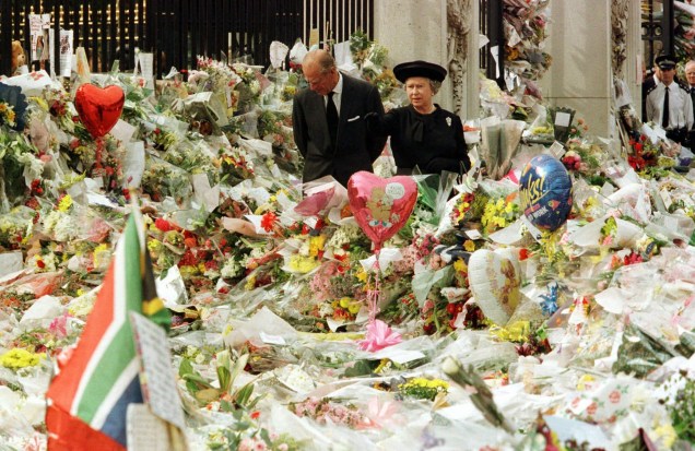 Com o príncipe Philip, vendo flores deixadas em memória de Diana do lado de fora do Palácio de Buckingham, em 1997 -