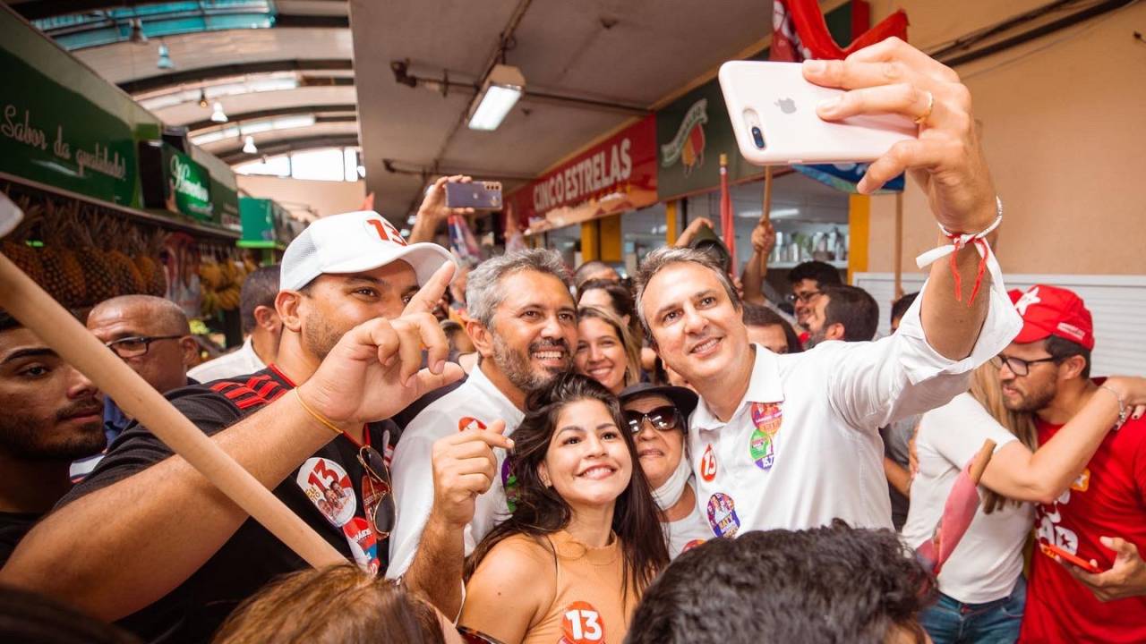 O ex-governador do Ceará Camilo Santana (PT) segura o celular para fazer selfie com eleitores e o candidato ao governo do estado Elmano de Freitas (PT)