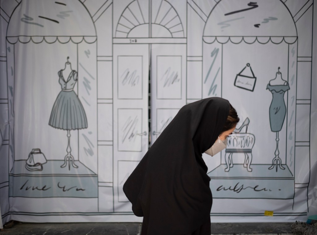 An Iranian woman walks past a shop window covered with a banner in northern Tehran on July 9, 2022. Iranian President Ebrahim Raisi called in a meeting with officials on Wednesday lack of compliance with hijab rules promotion of corruption in an Islamic country such as Iran. (Photo by Morteza Nikoubazl/NurPhoto via Getty Images)