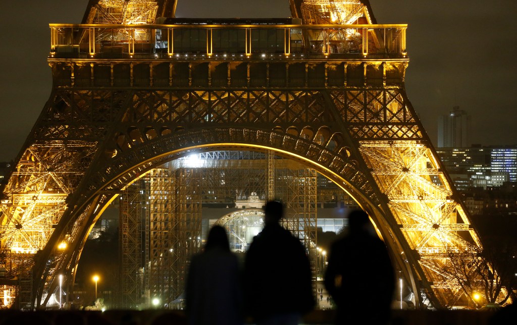 PARIS, FRANCE - JANUARY 14: People look at the illuminated Eiffel Tower at night as French Prime Minister, Jean Castex announces measures to combat the coronavirus (COVID-19) outbreak on January 14, 2021 in Paris, France. Jean Castex announced that a 6 p.m. curfew would apply throughout mainland France as of Saturday January 16. Vaccination will be extended from Monday to people suffering certain chronic conditions. Seven hundred vaccination centers will be open in France from January 18, according to the Prime Minister. (Photo by Chesnot/Getty Images)