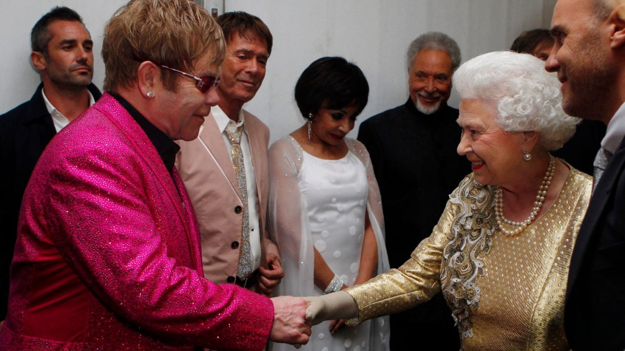 Rainha Elizabeth II cumprimenta Elton John durante celebração do Jubileu de Diamante no Palácio de Buckingham em 2012