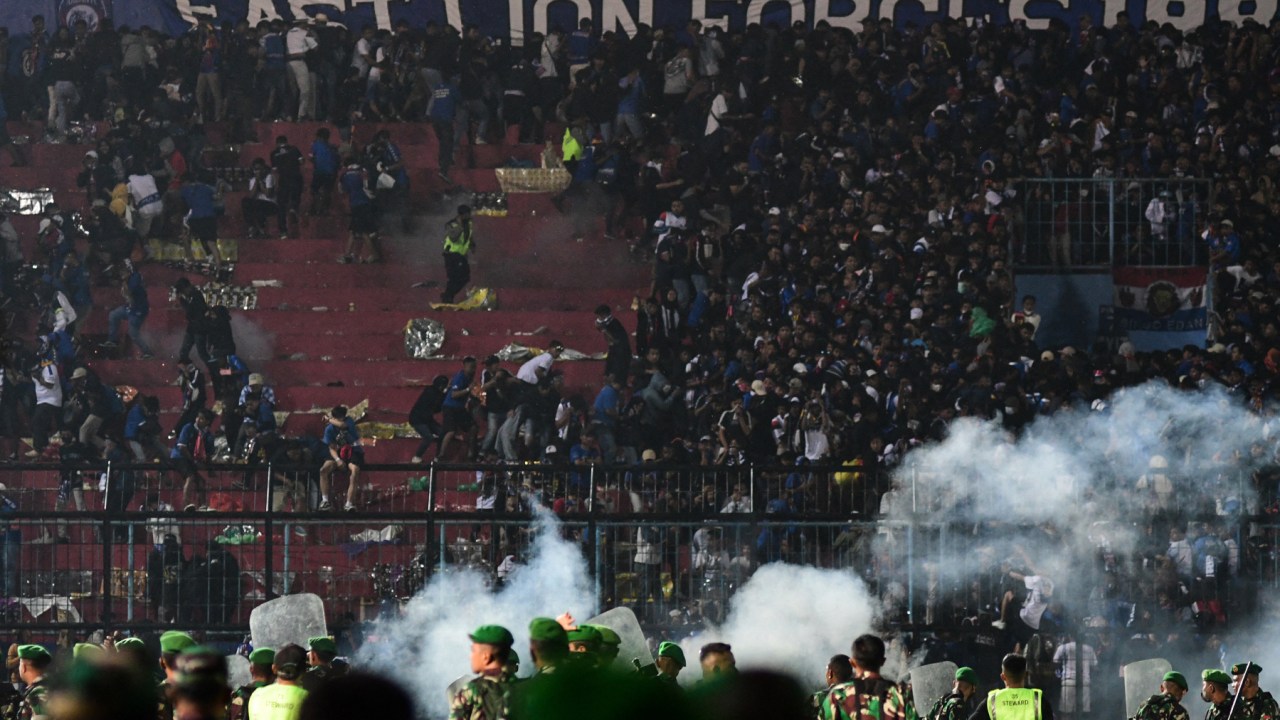 This picture taken on October 1, 2022 shows security personnel (lower) on the pitch after a football match between Arema FC and Persebaya Surabaya at Kanjuruhan stadium in Malang, East Java. - At least 127 people died at a football stadium in Indonesia late on October 1 when fans invaded the pitch and police responded with tear gas, triggering a stampede, officials said. (Photo by AFP)