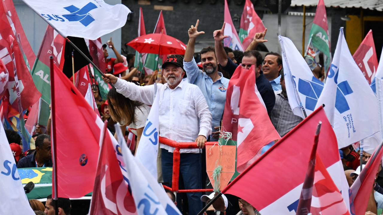 Brazilian former President (2003-2010) and presidential candidate for the leftist Workers Party (PT), Luiz Inacio Lula da Silva (C), greets his supporters during a rally at the Complexo do Alemao favela in Rio de Janeiro, Brazil, on October 12, 2022. - President Jair Bolsonaro, 67, exceeded polling predictions by coming a closer-than-expected second to ex-president Lula da Silva, 76, in a first election round on October 2. The two men will face off in a deeply polarized second round on October 30. (Photo by CARL DE SOUZA / AFP)