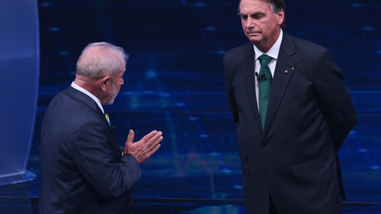 Brazilian former president (2003-2010) and presidential candidate for the leftist Workers Party (PT), Luiz Inacio Lula da Silva (L), speaks to Brazilian President and presidential candidate Jair Bolsonaro (R) during a televised presidential debate in Sao Paulo, Brazil, on October 16, 2022. - President Jair Bolsonaro and former President Luiz Inácio Lula da Silva face each other this Sunday night in the first face-to-face debate, in which they will try to take advantage 14 days before the second round of the presidential elections in Brazil. (Photo by NELSON ALMEIDA / AFP)