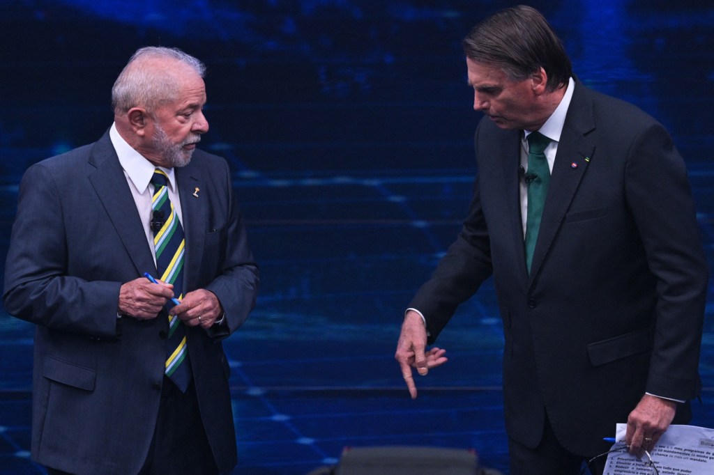 Brazilian former president (2003-2010) and presidential candidate for the leftist Workers Party (PT), Luiz Inacio Lula da Silva (L), and Brazilian President and presidential candidate Jair Bolsonaro (R) speak to each other during a televised presidential debate in Sao Paulo, Brazil, on October 16, 2022. - President Jair Bolsonaro and former President Luiz Inácio Lula da Silva face each other this Sunday night in the first face-to-face debate, in which they will try to take advantage 14 days before the second round of the presidential elections in Brazil. (Photo by NELSON ALMEIDA / AFP)