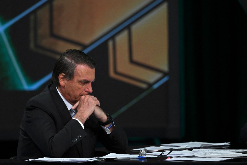 Brazilian President and presidential candidate Jair Bolsonaro looks at his desk full of papers during an interview televised by SBT broadcaster in Osasco, metropolitan area of Sao Paulo, Brazil, on October 21, 2022. - Veteran leftist Luiz Inacio Lula da Silva said on October 20 he is keeping an eye on poll numbers showing his lead narrowing over far-right incumbent Jair Bolsonaro for Brazil's October 30 presidential runoff, but confident he will win. (Photo by Nelson ALMEIDA / AFP)