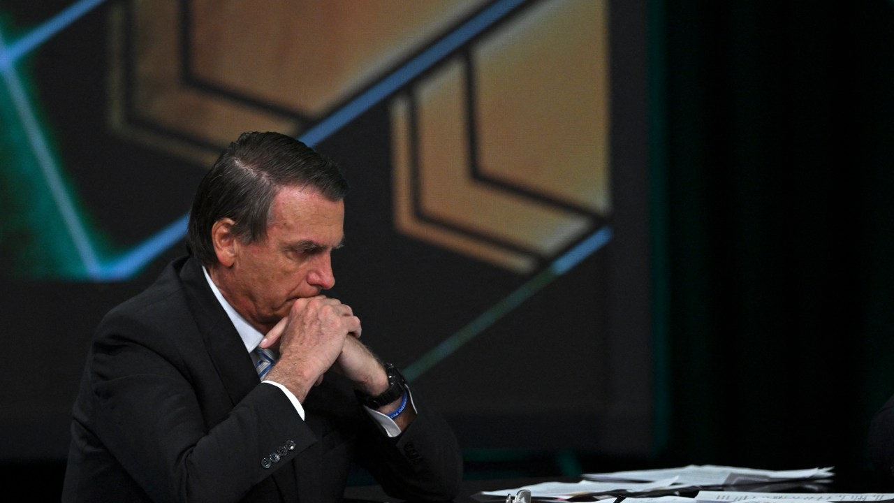 Brazilian President and presidential candidate Jair Bolsonaro looks at his desk full of papers during an interview televised by SBT broadcaster in Osasco, metropolitan area of Sao Paulo, Brazil, on October 21, 2022. - Veteran leftist Luiz Inacio Lula da Silva said on October 20 he is keeping an eye on poll numbers showing his lead narrowing over far-right incumbent Jair Bolsonaro for Brazil's October 30 presidential runoff, but confident he will win. (Photo by Nelson ALMEIDA / AFP)