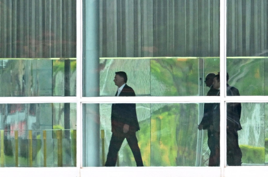 Brazilian President Jair Bolsonaro (C) walks at Alvorada Palace in Brasilia, on October 31, 2022, a day after the presidential run-off election. - A tense Brazil awaited Jair Bolsonaro's next move Monday, as the far-right incumbent remained silent after losing a razor-thin runoff presidential election to veteran leftist Luiz Inacio Lula da Silva -- who now faces a tough to-do list. Bolsonaro was defeated by Lula with a score of 51 percent to 49 percent -- the tightest race since Brazil returned to democracy after its 1964-1985 military dictatorship. (Photo by EVARISTO SA / AFP)