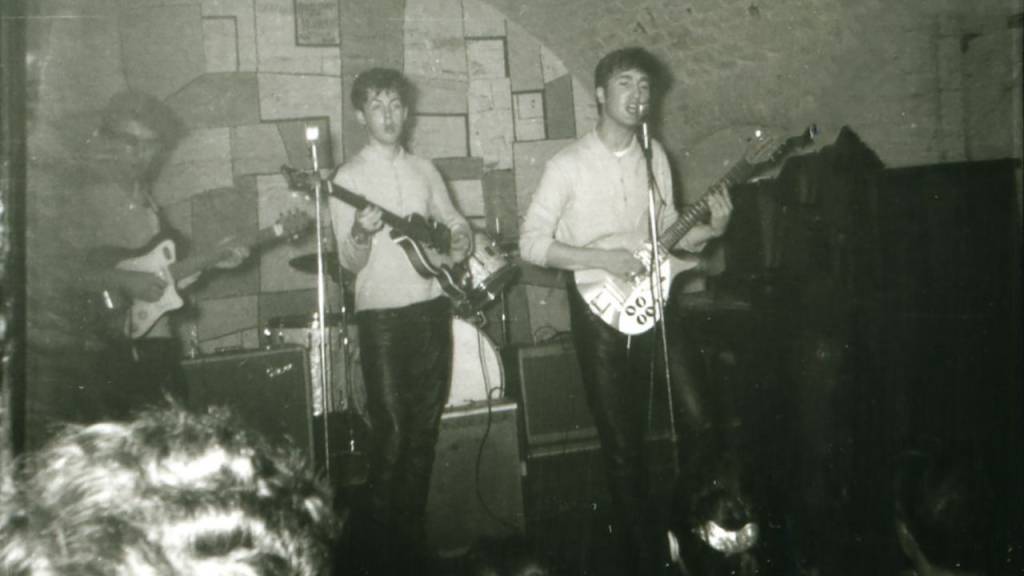 Uma imagem rara de 1961 mostrando (esq.) George Harrison, Paul McCartney e John Lennon. O baterista Pete Best está parcialmente visível -