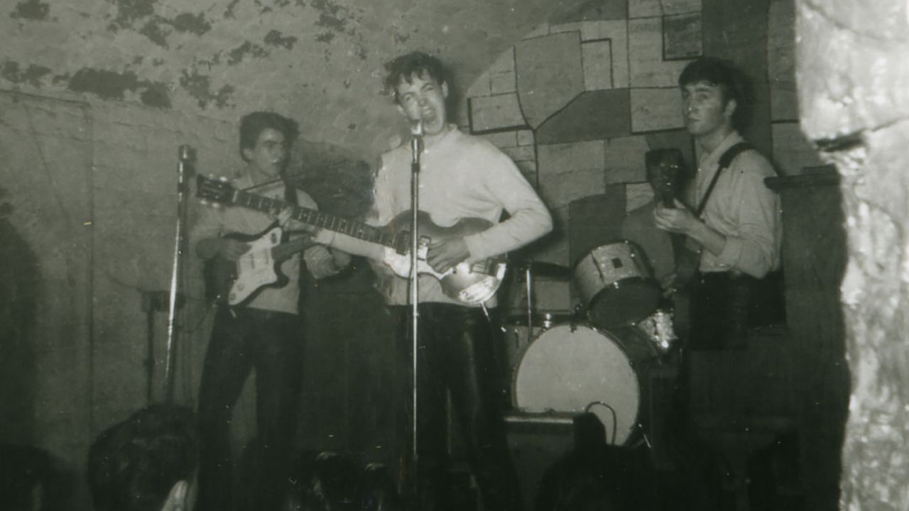 Uma imagem rara mostrando (esq.) George Harrison, Paul McCartney e John Lennon. O baterista Pete Best está parcialmente visível