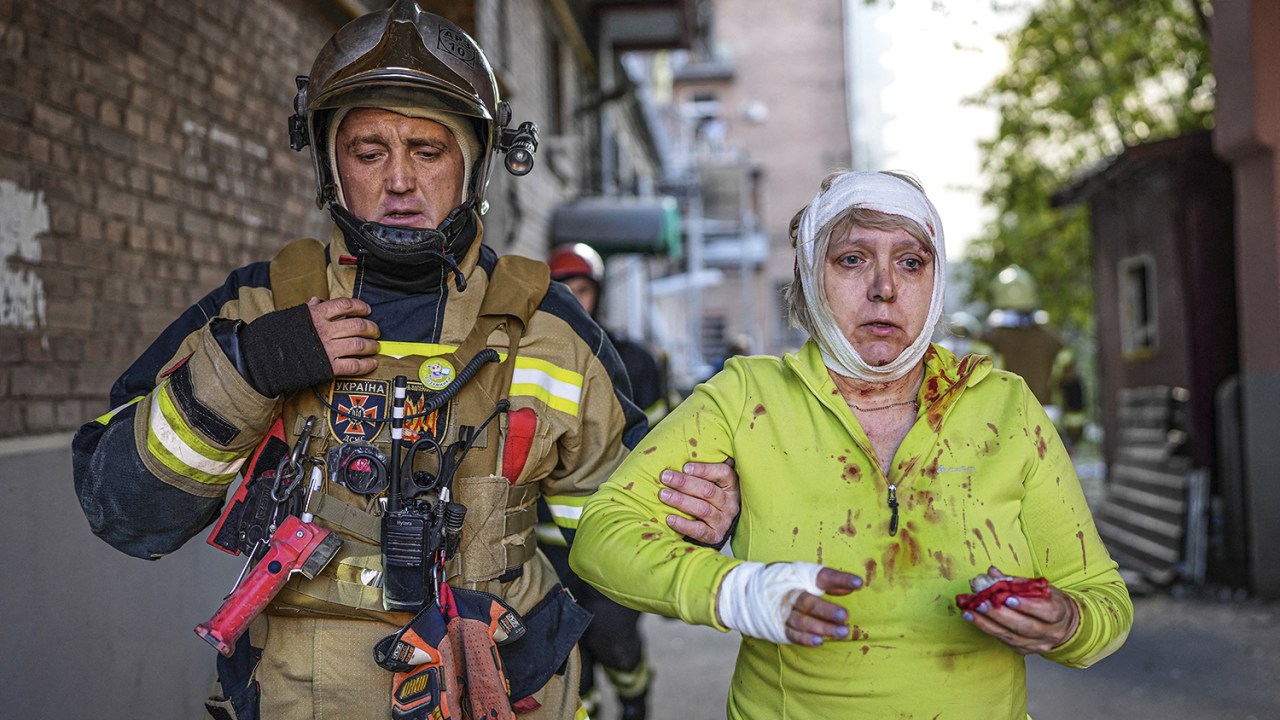 CIVIS NA MIRA - Socorrista atende mulher ferida em Kiev: a Rússia exibe seu poder de fogo -