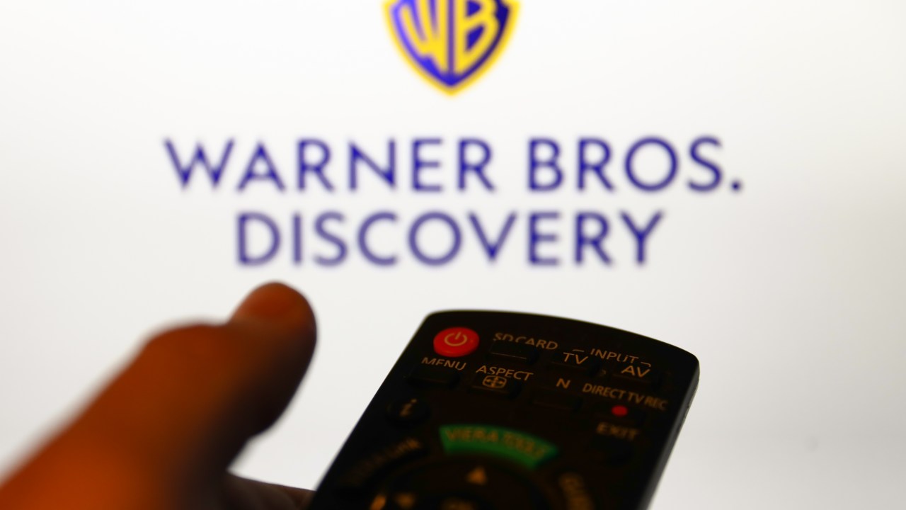 Warner Bros. Discovery logo displayed on a screen and a tv remote control are seen in this illustration photo taken in Krakow, Poland on April 9, 2022. (Photo by Jakub Porzycki/NurPhoto via Getty Images)