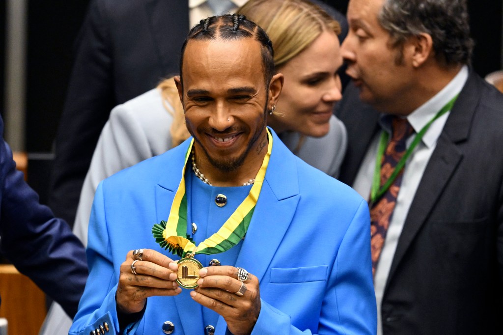 British F1 driver Lewis Hamilton shows his medal after being awarded the Honorary Brazilian Citizenship, during a ceremony at the National Congress, in Brasilia on 7 November 2022. (Photo by EVARISTO SA / AFP)a