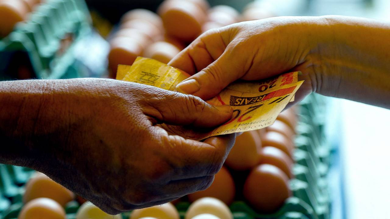 (FILES) In this file photo taken on August 25, 2022, a customer pays in cash at an eggs stall at the street market in Sao Paulo, Brazil, on August 25, 2022. - Consumer prices in Brazil grew 0.59% in October, interrupting three consecutive months of deflation, the Brazilian statistics institute (IBGE) said on Thursday November 10, 2022. (Photo by Miguel SCHINCARIOL / AFP)