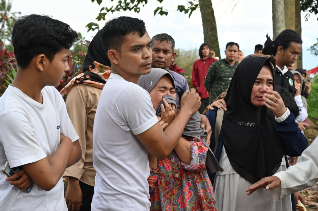 Relatives cry during the funeral of 48-year-old victim Husein, who was killed while building a house, at a village near Cianjur on November 22, 2022, following a 5.6-magnitude earthquake. - The death toll from an earthquake on Indonesia's main island of Java jumped to 268 on November 22, as rescuers searched for survivors in the rubble and relatives started to bury their loved ones. (Photo by ADEK BERRY / AFP)